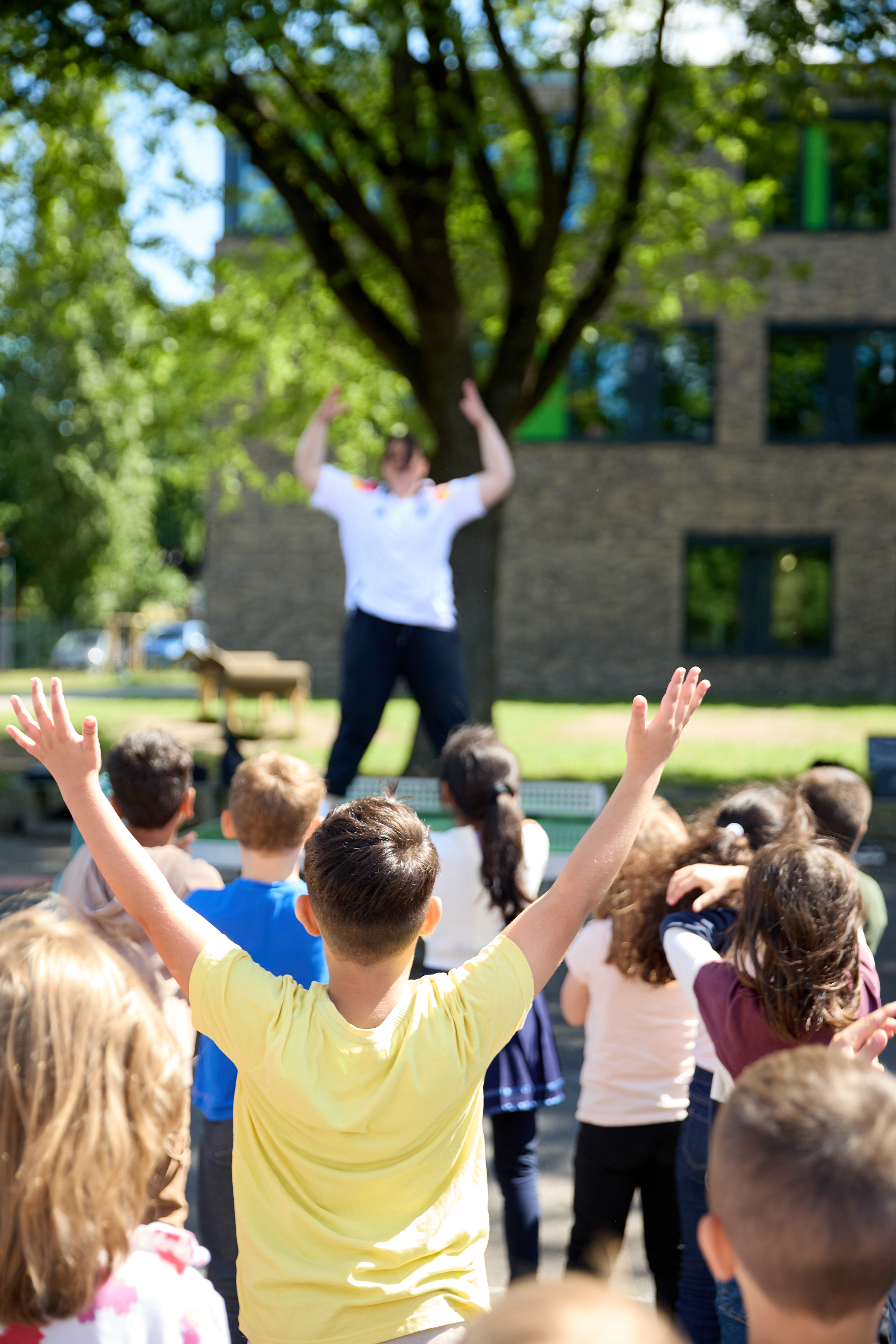 Kinder mit erhobenen Armen bei einer bewegten Aktion im Freien